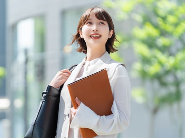 オフィス街を笑顔で歩く女性